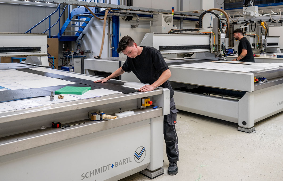 Ein junger Mensch misst eine Kunststoffplatte ab und zeichnet die Änderungen ein.