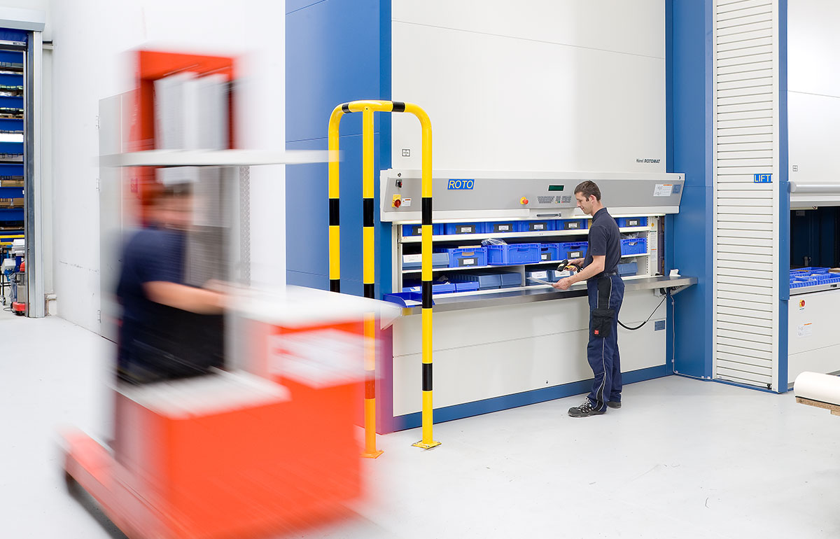 Ein junger Mann arbeitet an einer Sortiermaschine, während links von ihm ein Gabelstapler vorbeifährt.