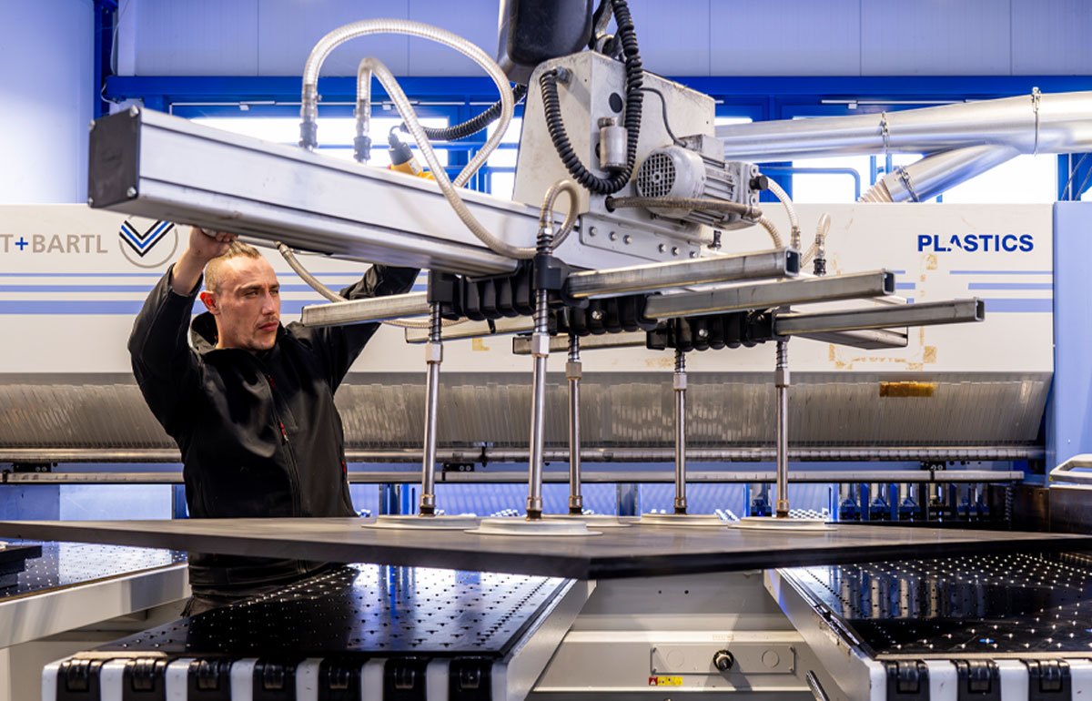 Ein Arbeiter steuert eine Maschine, die eine Platte fixiert.